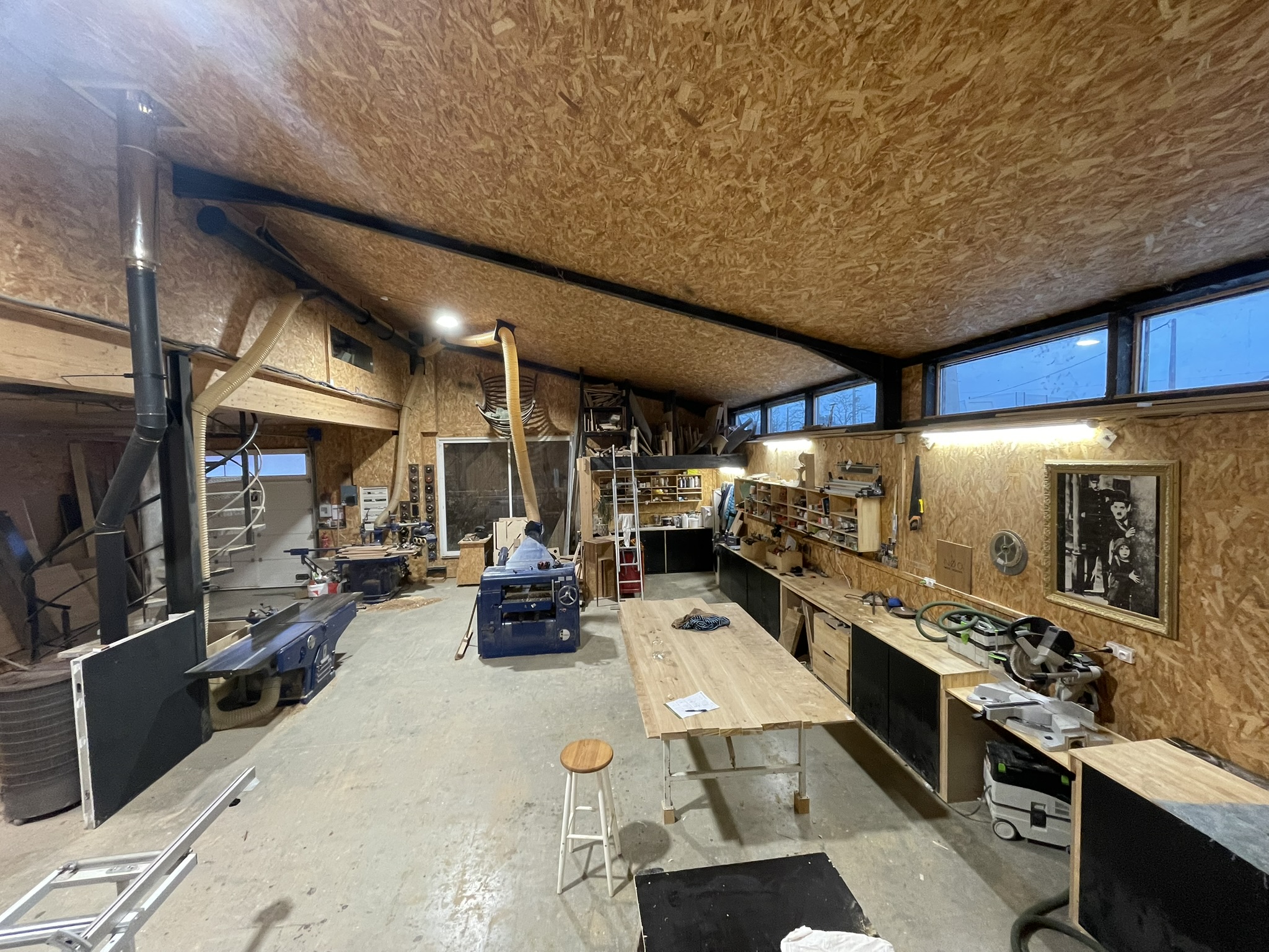 Vue intérieure de l'atelier d'ébénisterie Aux Bois d'Armand, avec établi, outils de menuiserie et pièces de bois en cours de fabrication.